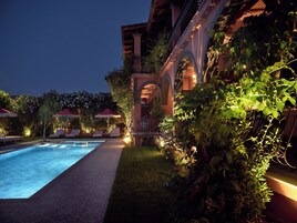 Una piscina al aire libre, sombrillas, sillones reclinables de piscina