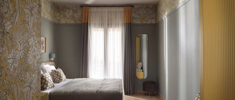 Un dormitorio con cama, ventilador de techo, espejo y papel tapiz estampado.