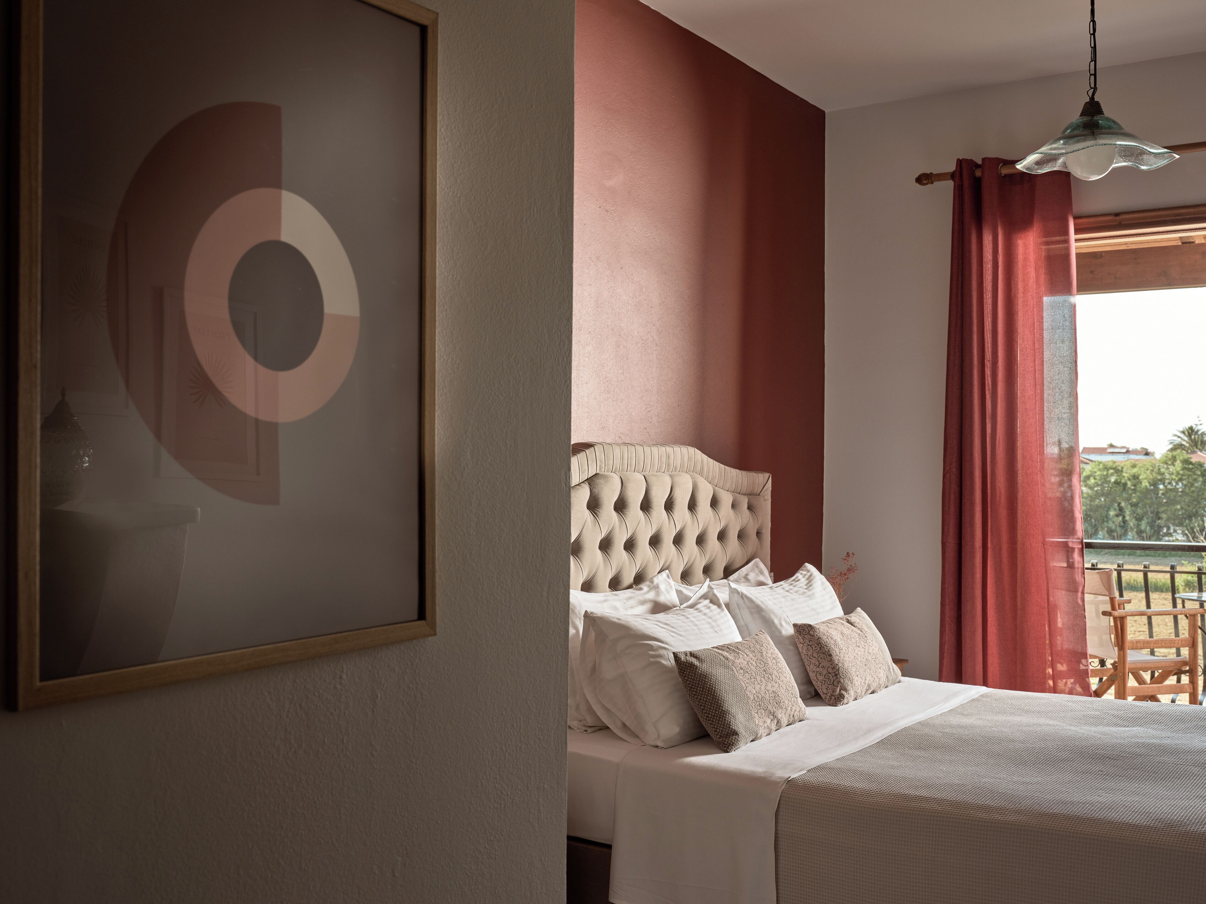 A bedroom with a large bed, a headboard, and a window with curtains.