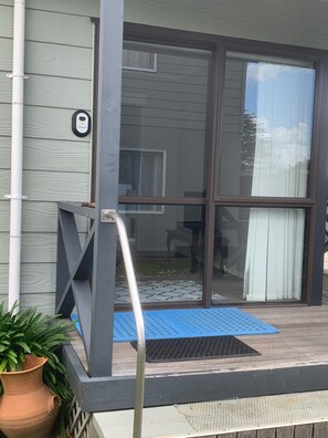 A house entrance with a sliding glass door, a blue mat, and a potted plant. - Agapantha Cottage Retreat (Hamilton City)