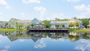 Une rangée de maisons de ville modernes à deux étages, avec un plan d’eau aux reflets chatoyants au premier plan.