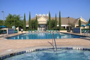 A swimming pool with a 2 ft 9 in depth marker, surrounded by lounge chairs and a building with a classical architectural style in the background.