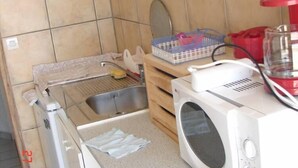 Une cuisine compacte équipée d’un évier, d’un four à micro-ondes et d’un petit plan de travail.