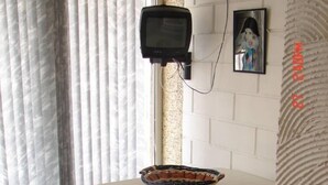 Une pièce avec une table blanche, un téléviseur fixé au mur, un tableau encadré et un canapé à motifs.