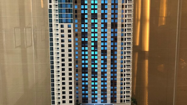 Une maquette d’un immeuble de grande hauteur, doté de nombreux étages, de balcons et d’un hall d’entrée central avec une piscine.