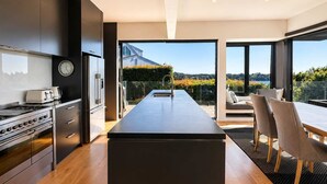 A modern kitchen with a central island, stainless steel appliances, and a dining area with a view.