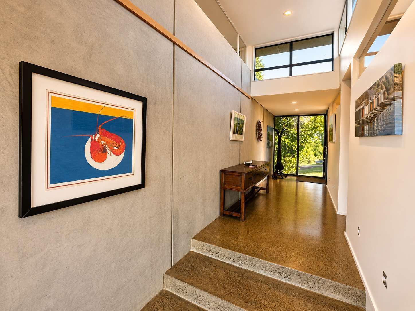 A modern interior with a staircase, framed artwork, and a view to the outdoors.
