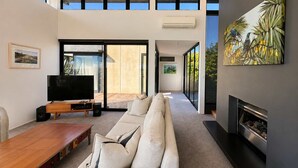 A modern living room with a sofa, TV, and fireplace.