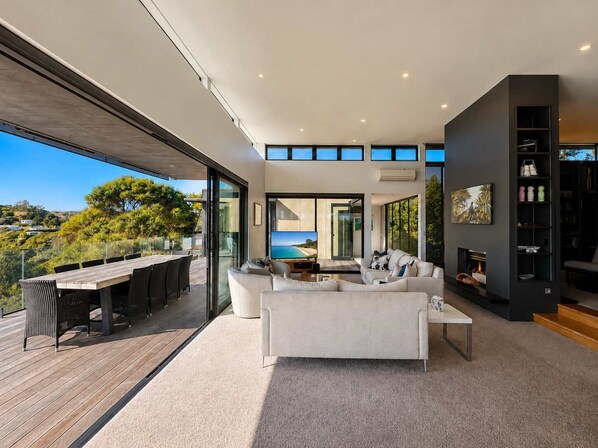 A modern living room with a large window, a fireplace, and a view of the outdoors.
