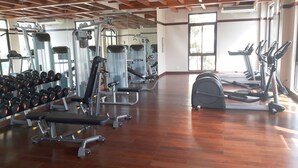 A gym with various exercise equipment, including treadmills and weight machines, and a wooden floor. - Lux. 2 BR Condo Seaside Close to SM Seaside Megamall-Huge pools (Cebu City)