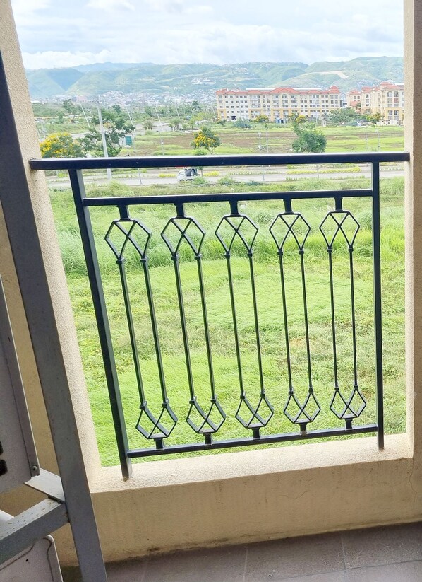 A balcony with a metal railing overlooking a green landscape and distant buildings. - Lux. 2 BR Condo Seaside Close to SM Seaside Megamall-Huge pools (Cebu City)