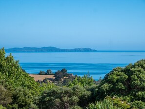 Paisagem costeira com vista clara para o mar e montanhas ao longe.