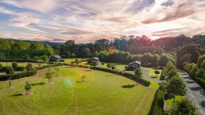 A residential area with multiple houses surrounded by well-maintained lawns and trees. - Matakana Oasis - Beauregard Cottages (Matakana)