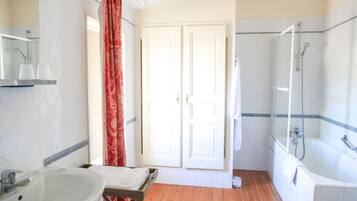 Une salle de bain avec un lavabo, un miroir, une douche et deux portes.