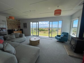 Una sala de estar moderna con un sofá gris, un sillón azul, una mesa de centro redonda y un televisor sobre un mueble.