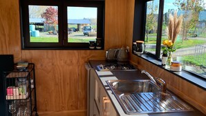 Una cucina moderna con pareti in legno, un lavello in acciaio inossidabile e una finestra che si affaccia su un paesaggio rurale.