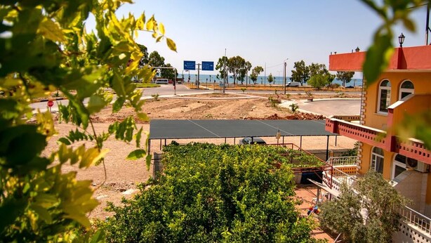 A view of a construction site with a building in the background, a road with a stop sign, and a clear sky. - Baykal Pansiyon (Finike)