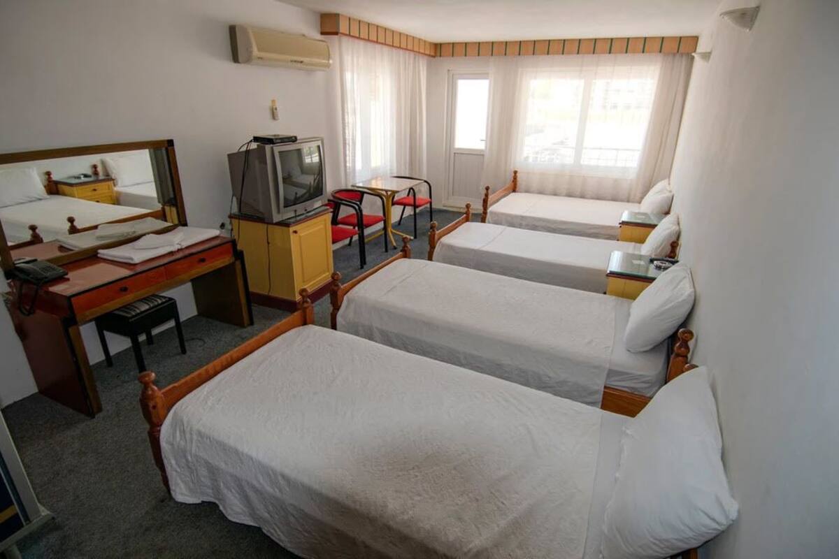 A hotel room with two single beds, a desk with a chair, a television, and a mirror.
