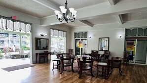 A spacious room with wooden flooring, a chandelier, and multiple dining tables with chairs. - RENOVATED Kona Studio By The Ocean!!! (Kailua)