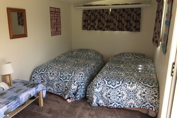 A small, cozy room with two beds, a small table, and a mirror.