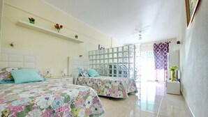 Una habitación de hotel con dos camas, un ventanal con vistas y un ventilador de techo.