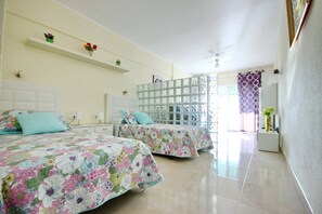 Una camera d'albergo con due letti, un'ampia finestra vista e una ventola a soffitto.