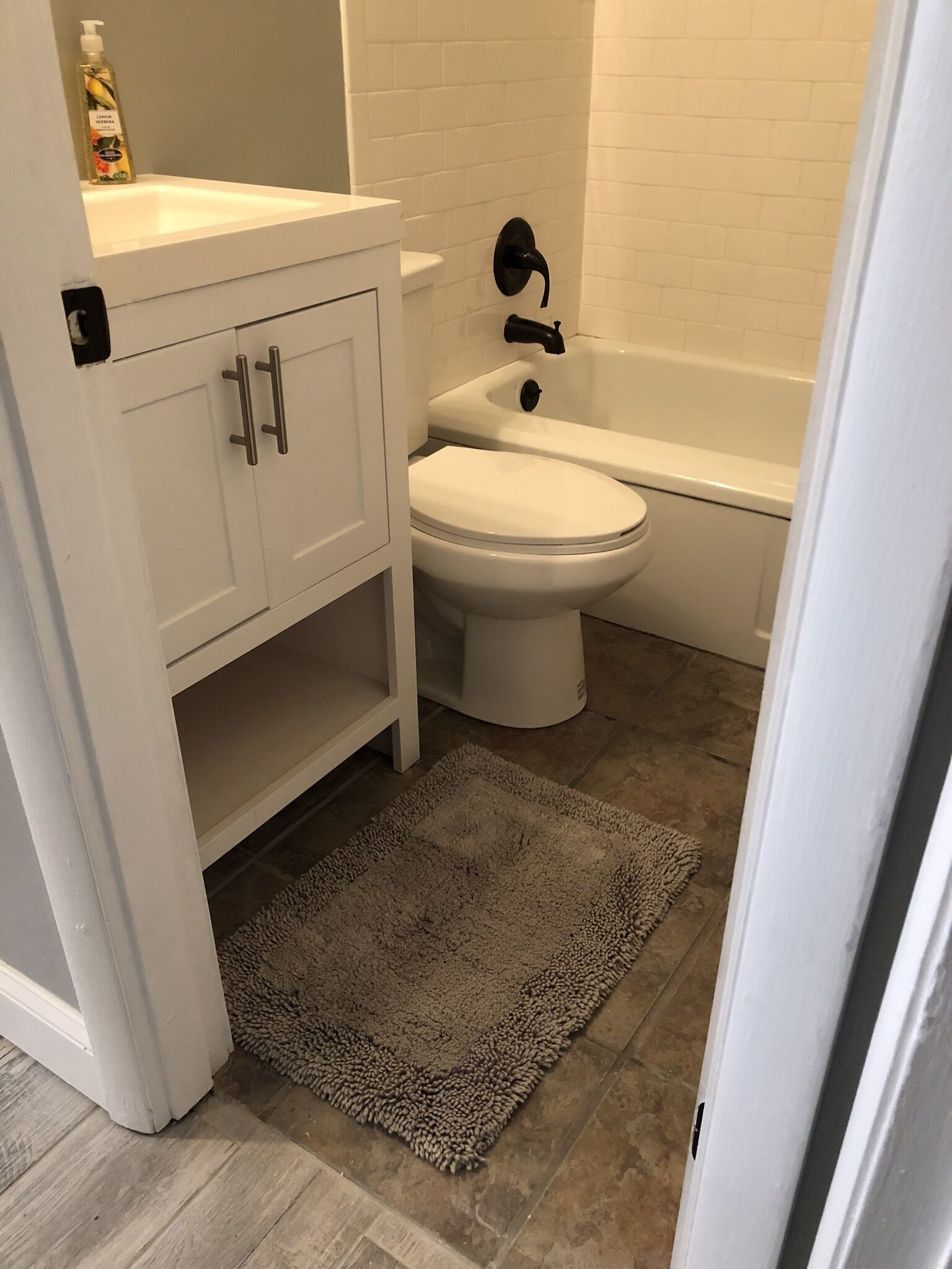 Un baño con inodoro y lavamanos blancos, además de una bañera.