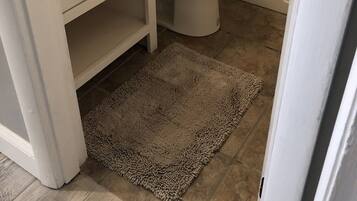 Un baño con inodoro y lavamanos blancos, además de una bañera.