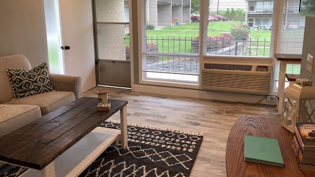 A living room with a sofa, a coffee table, a rug, and a bookshelf.