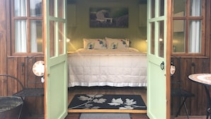 A cozy bedroom with a bed, a painting, and a small table with chairs.