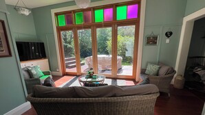 A living room with a wicker sofa, a glass coffee table, and a television on a stand.