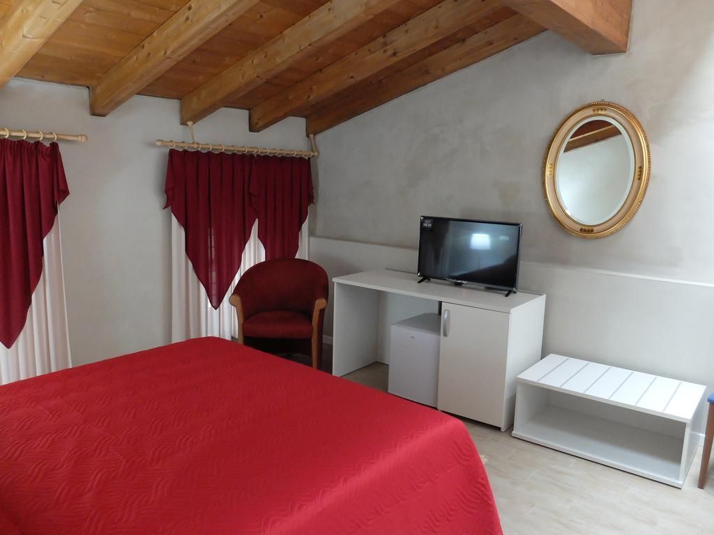Een slaapkamer met een bed, bureau met een televisie, een stoel en een spiegel.