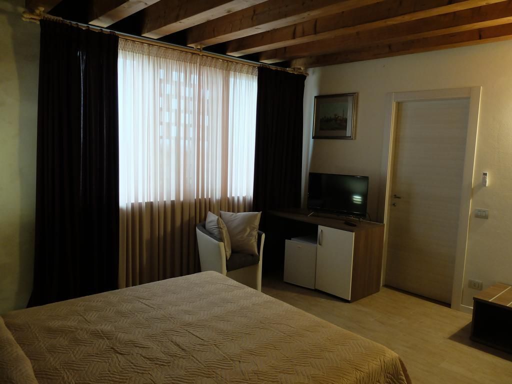 Un dormitorio con cama, escritorio, televisor y puerta.