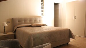 A bedroom with a bed, a chair, a nightstand, and a wardrobe. - B&B Eldorado (Sommacampagna)