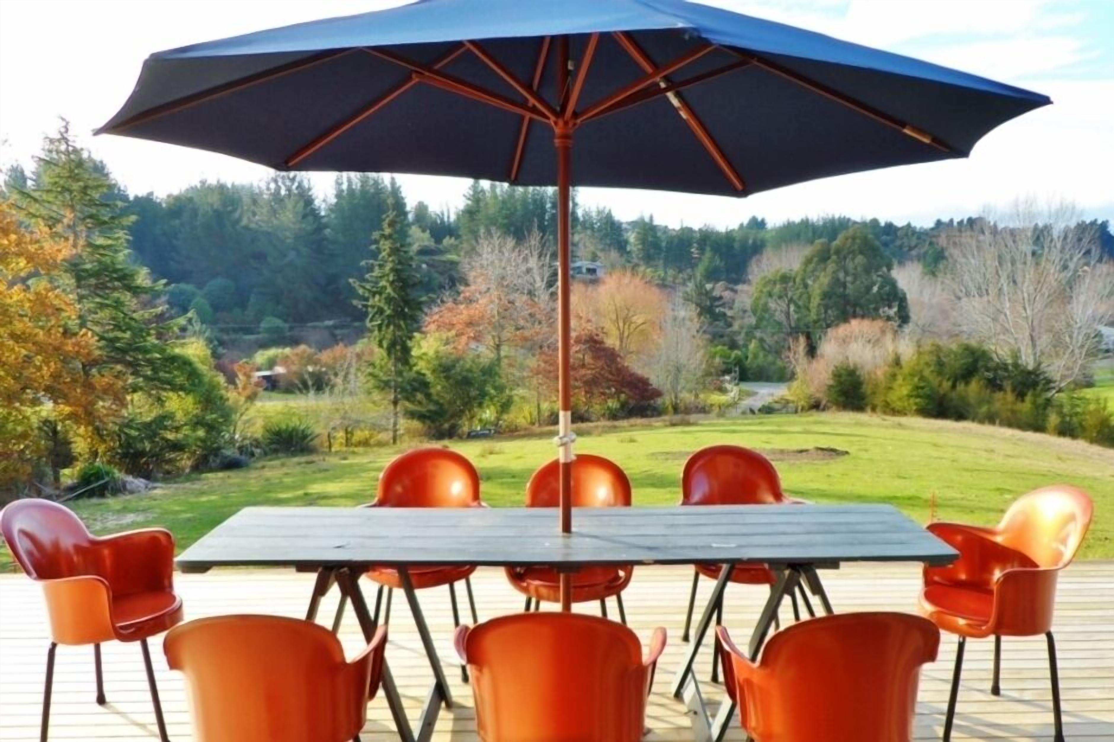 A deck with a table and chairs, an umbrella, and a view of a forested area.