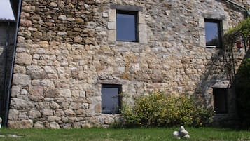 A stone building with three windows and a small garden area.