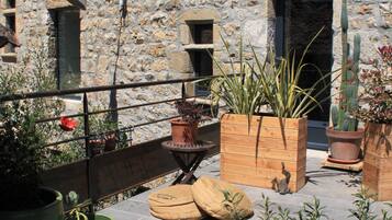 A stone building with a rooftop garden featuring potted plants and a wooden bench.