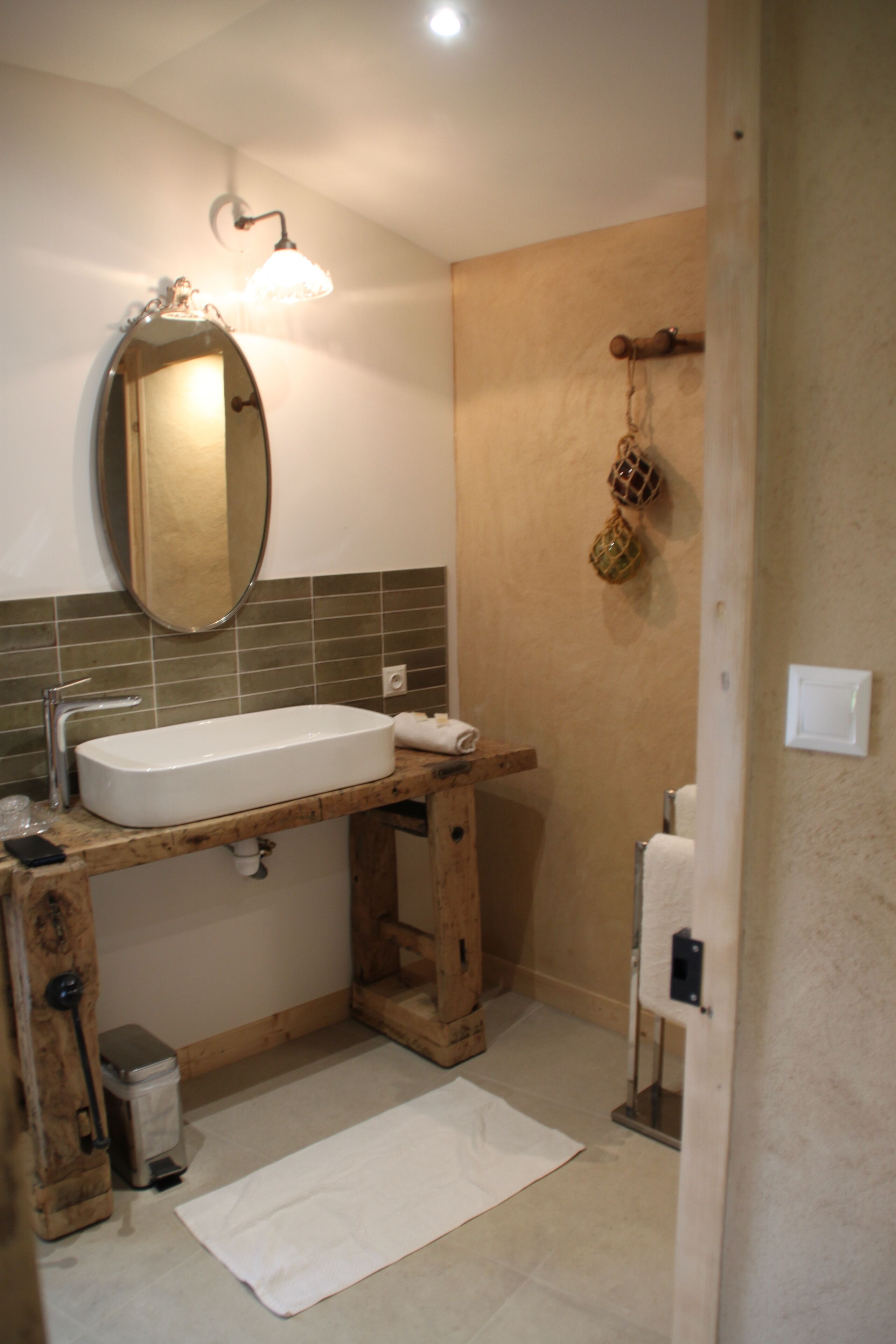A bathroom with a wooden vanity, a white sink, a mirror, and a towel rack.