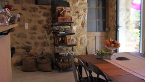 Un interior rústico con pared de piedra, muebles de madera y un frutero sobre la mesa.