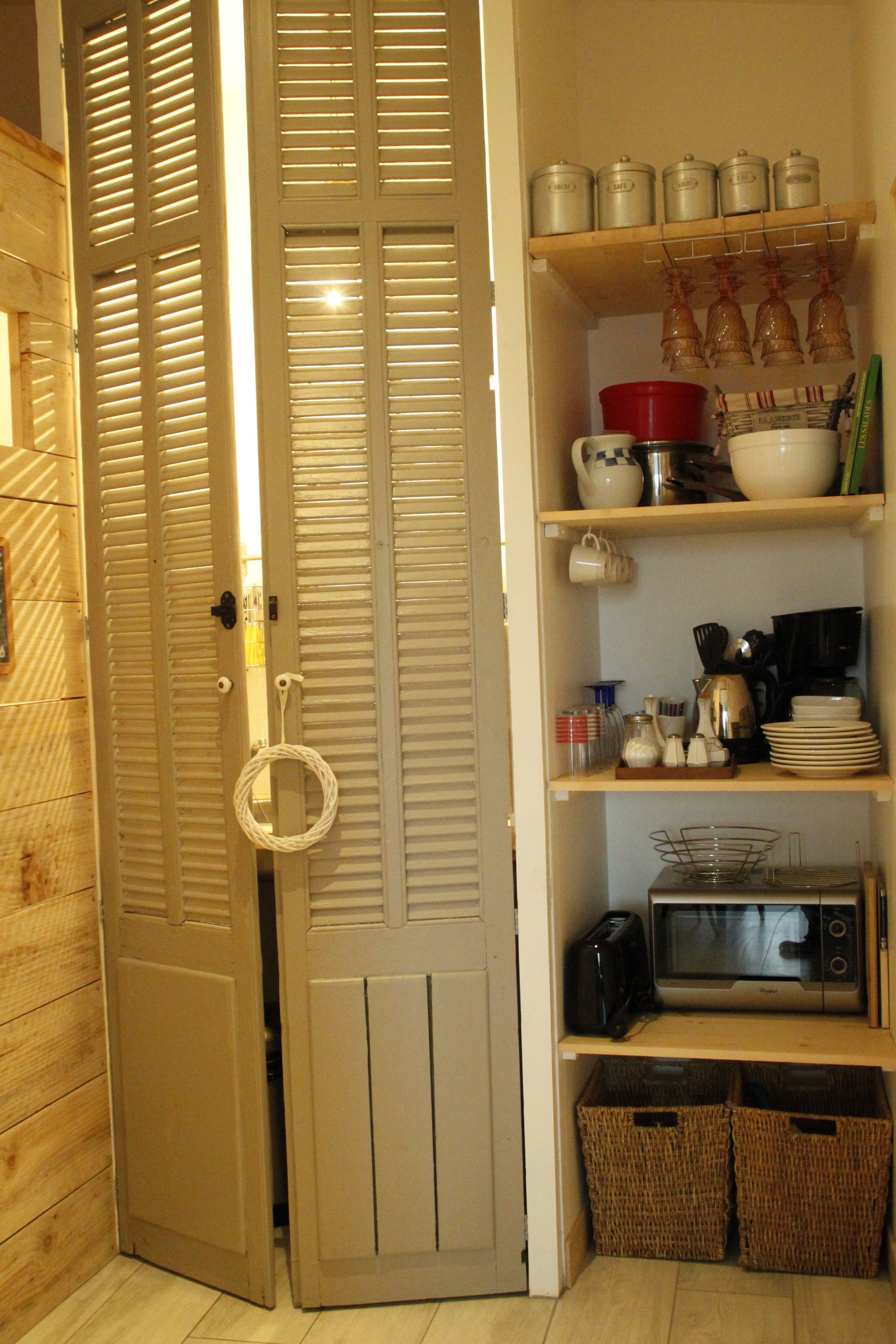 A kitchen with wooden cabinets, a microwave, and a toaster. There are baskets under the cabinets and a door with a handle.