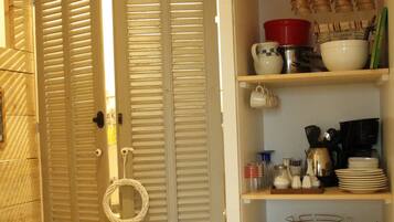 A kitchen with wooden cabinets, a microwave, and a toaster. There are baskets under the cabinets and a door with a handle.