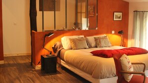 Un dormitorio con una cama grande, una mesita de noche, una lámpara de escritorio, una silla y un espejo.