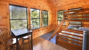 A cabin interior with a bunk bed, a dining table with chairs, and large windows with blinds. - Beautiful secluded cottage with gated privacy. (Smithville)