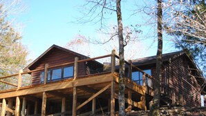 A cabin with a wooden deck and a covered porch. - Beautiful secluded cottage with gated privacy. (Smithville)