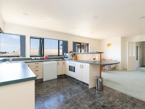 A modern kitchen with a built-in oven, a sink, and a window overlooking a rooftop.