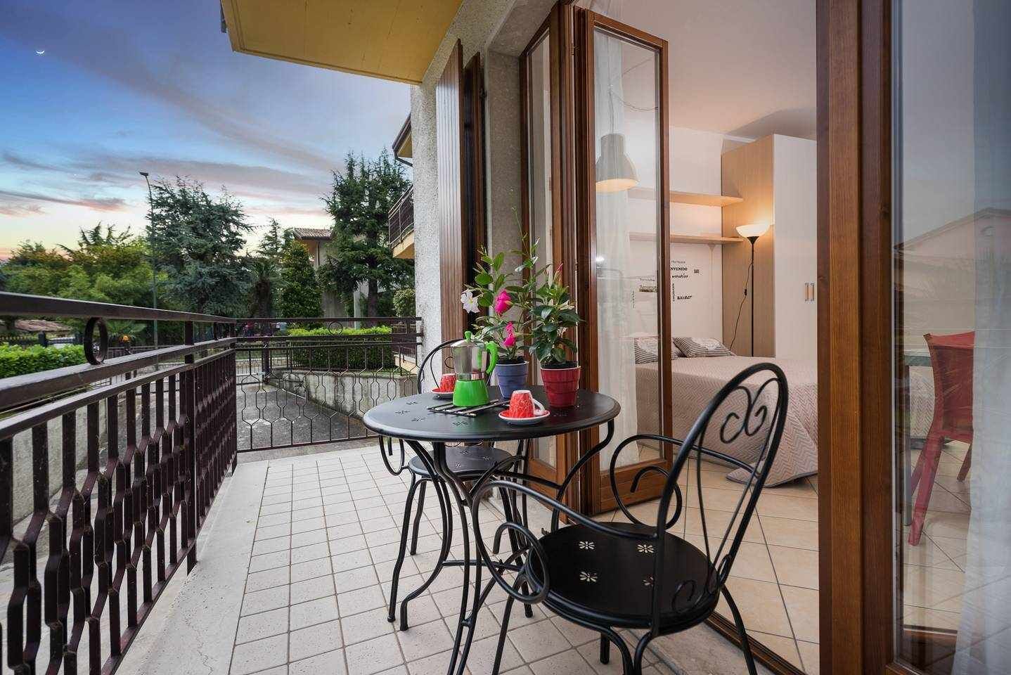 Un balcón con una mesa y sillas, una planta en maceta y vistas del entorno.
