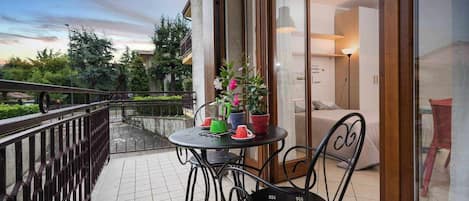 Un balcón con una mesa y sillas, una planta en maceta y vistas del entorno.