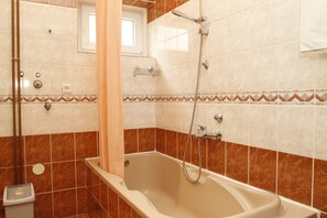 A bathroom with a bathtub, shower, and a window. - Apartments and Rooms Krizmanic (Plitvicka Jezera)
