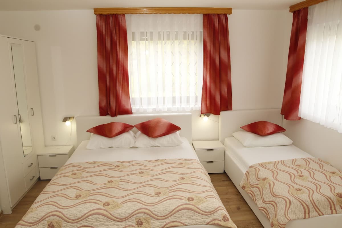 Ein Schlafzimmer mit zwei Betten, einem Kleiderschrank und einem Fenster mit Vorhängen.