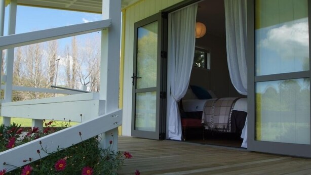 A bedroom with a bed, curtains, and a view of the outdoors.